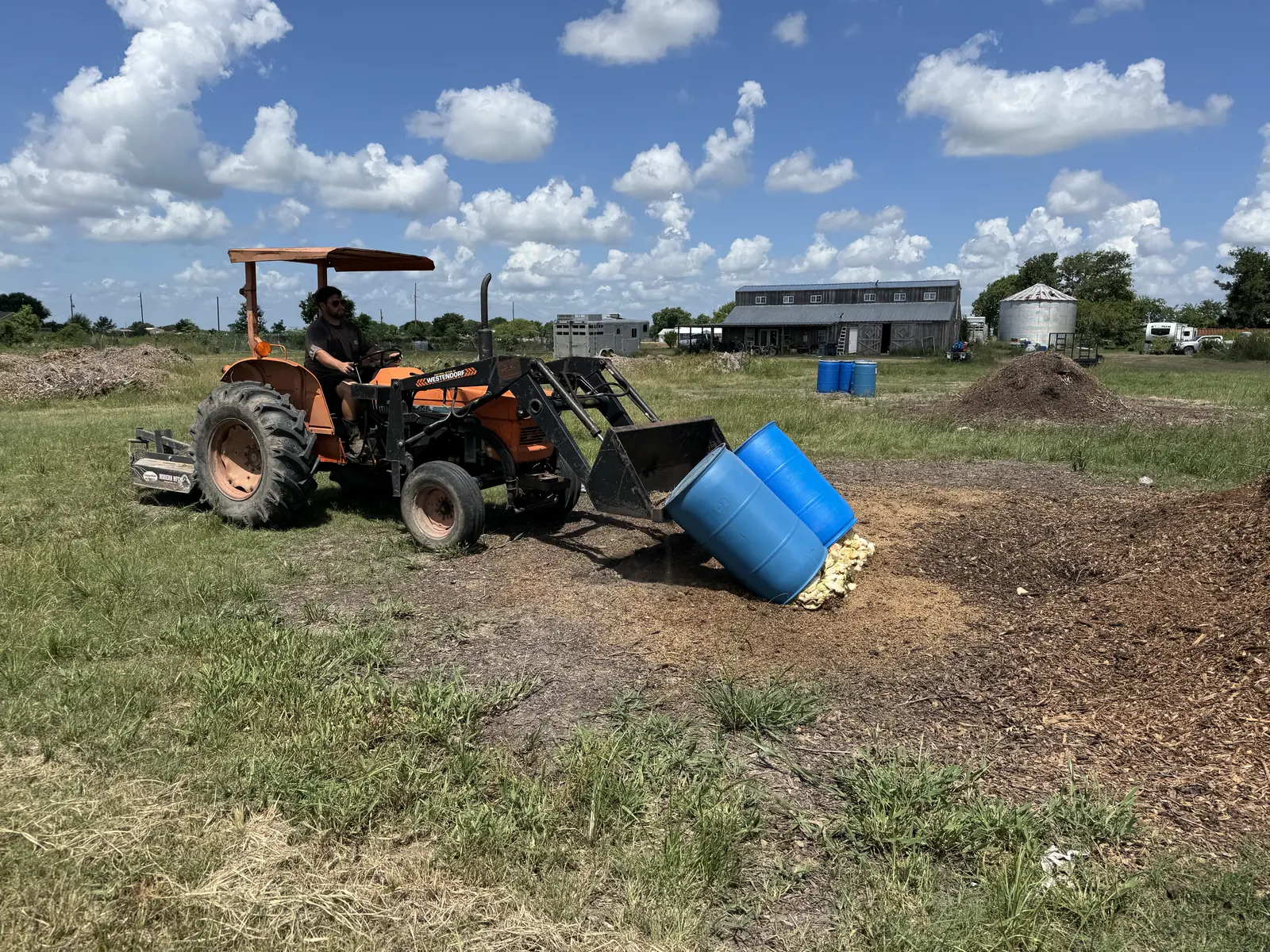 Collected food waste being emptied from a drum onto a compost pile at a Texas partner farm