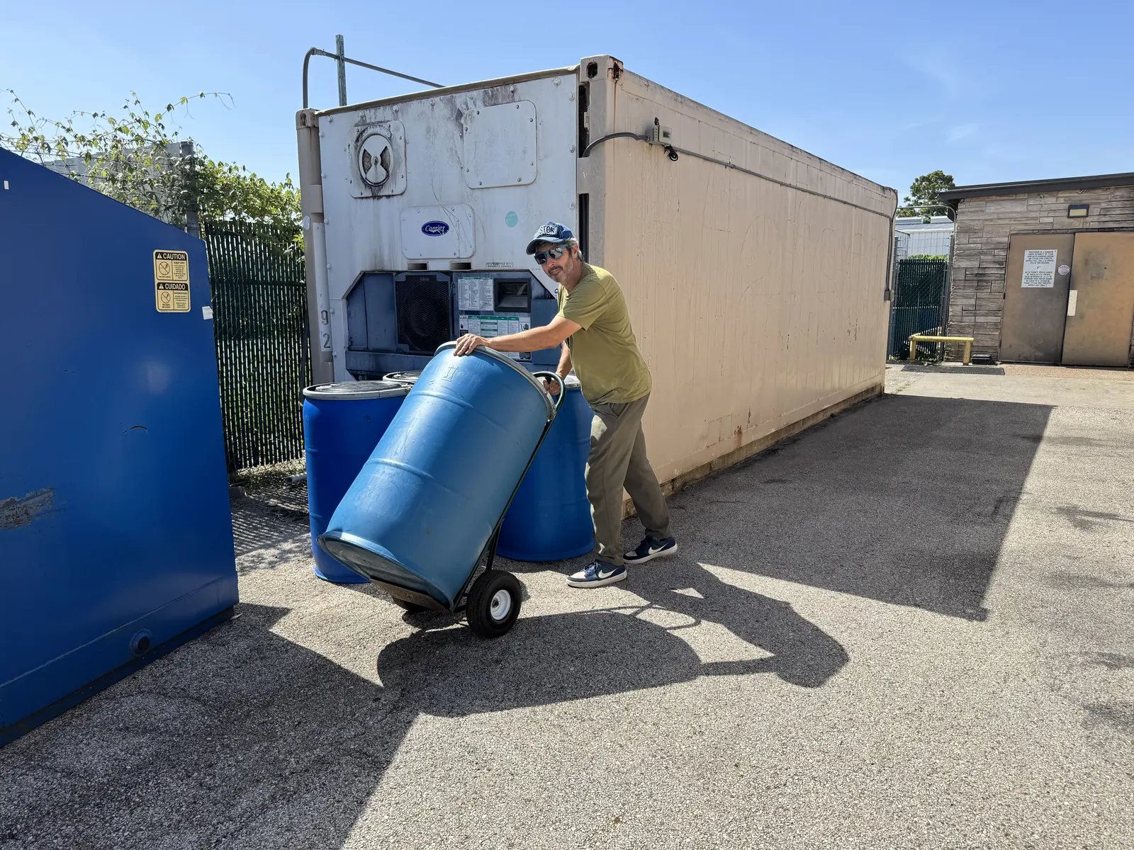Scotty loading a sealed food waste drum during a commercial pickup in the Houston area