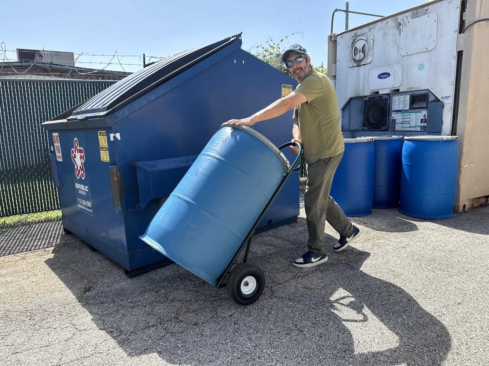 OnFarmCompost founder Scotty moving a sealed 55-gallon drum during a commercial food waste pickup